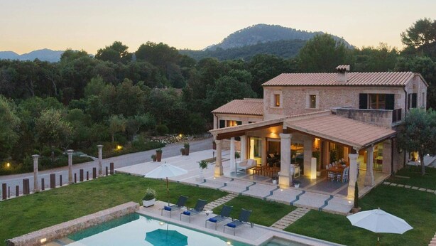 Una casa grande con piscina, mobiliario exterior y vistas del paisaje circundante.