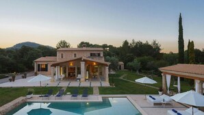 Una casa grande con piscina, mobiliario exterior y jardín.