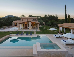 A large house with a swimming pool, outdoor seating, and a garden.