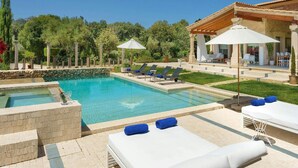 Ein Poolbereich mit Liegestühlen, einer Pergola und einer überdachten Sitzgelegenheit.
