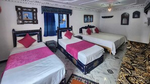 A hotel room with three beds, a patterned carpet, and decorative ceiling and wall elements. - blue city (Chefchaouen)