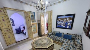 A room with a patterned sofa, a decorative ottoman, and a chandelier. - blue city (Chefchaouen)