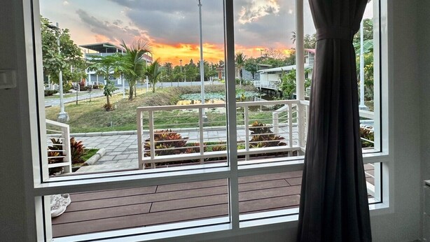 Une pièce dotée d’une grande fenêtre donnant sur un jardin et offrant une vue sur le coucher de soleil.
