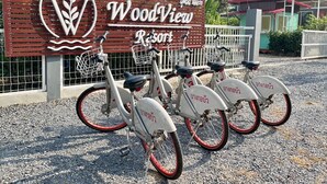 Une enseigne pour le complexe hôtelier WoodyView, avec un logo et le nom de l’établissement, et trois vélos garés devant.