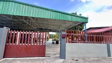 A covered outdoor area with a green roof, a red and white fence, and a mailbox.