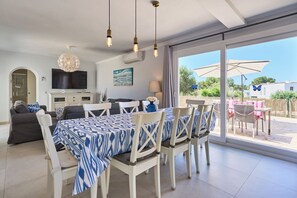 A modern living room with a dining area, large windows, and a view of the outdoors.