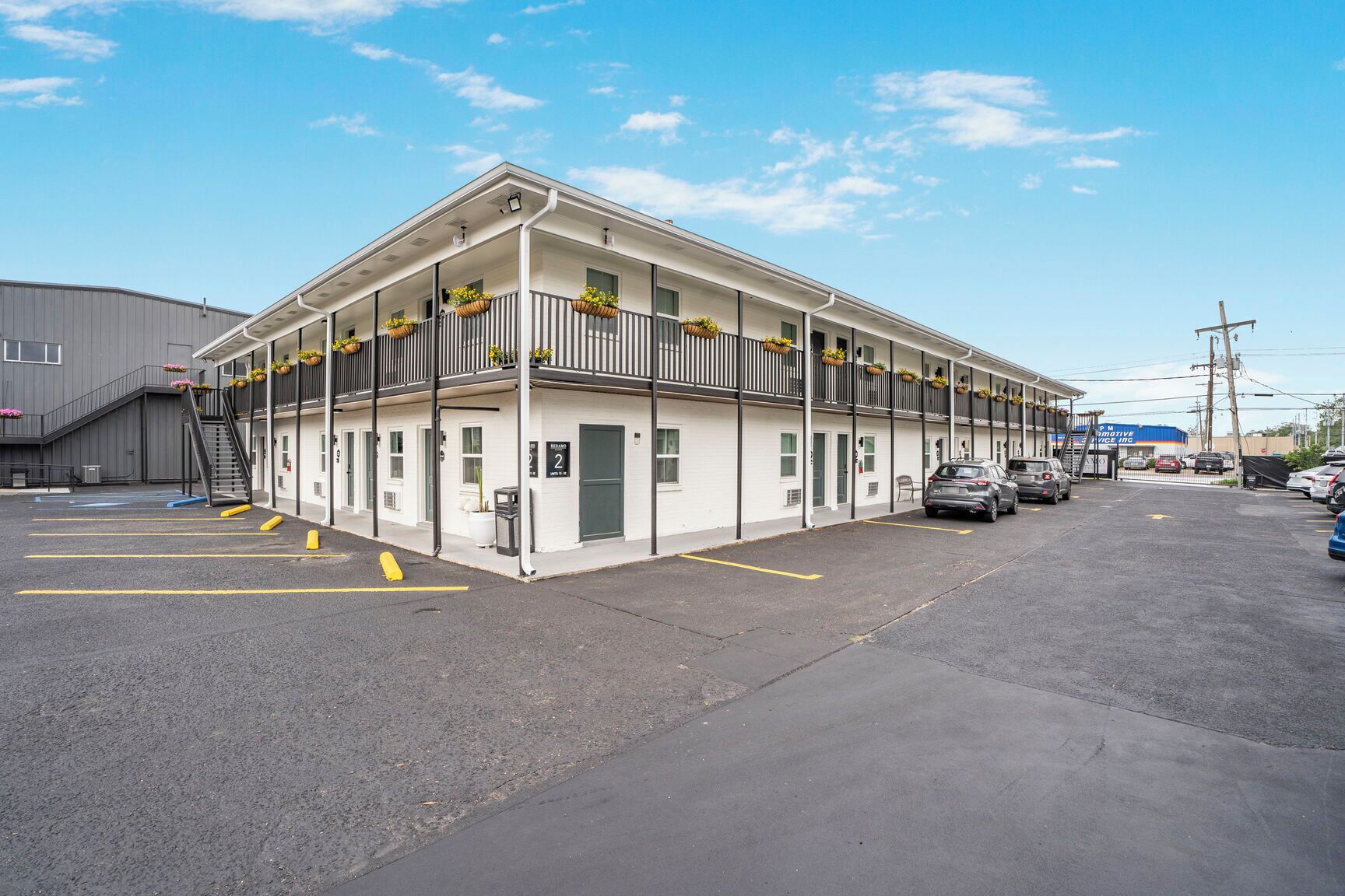 Een motel met een gebouw van twee verdiepingen, een overdekte parkeerplaats en een duidelijke ingang.