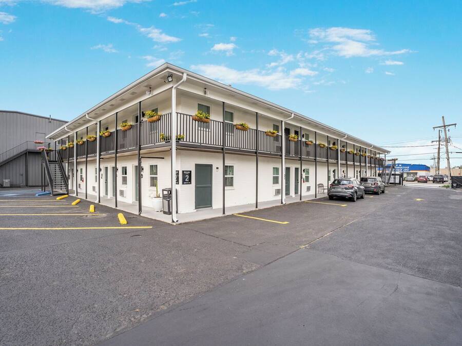 Un motel composé d’un bâtiment à deux étages, d’un espace de stationnement couvert et d’une entrée bien visible.
