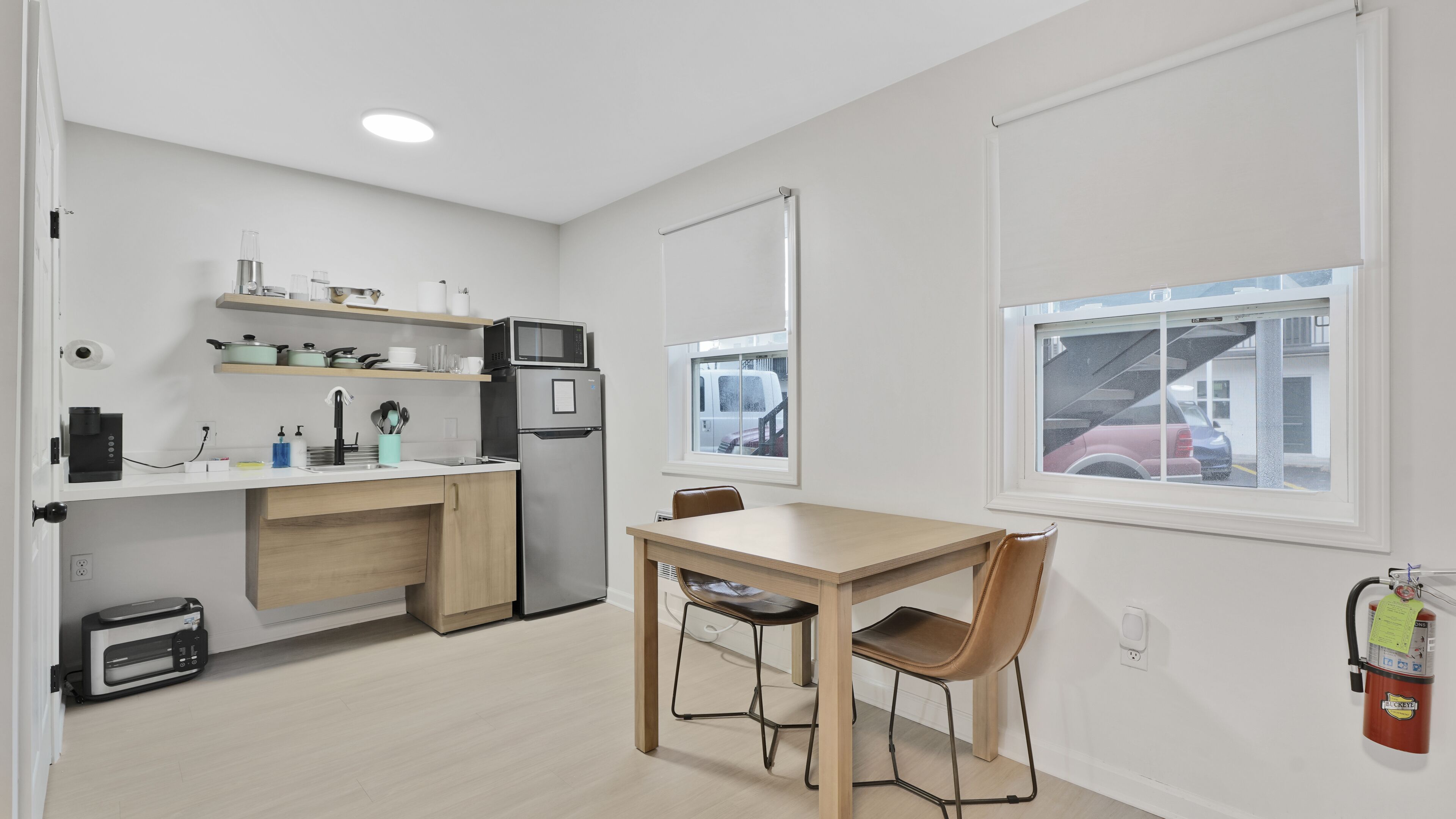Una cocina moderna con microondas, refrigerador y comedor con mesa y sillas.