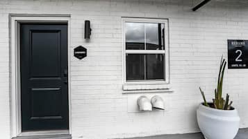 A white brick building with a black door, a window, and a sign indicating "Laundry" and "Redamo Suites 2 Units: 13-32".