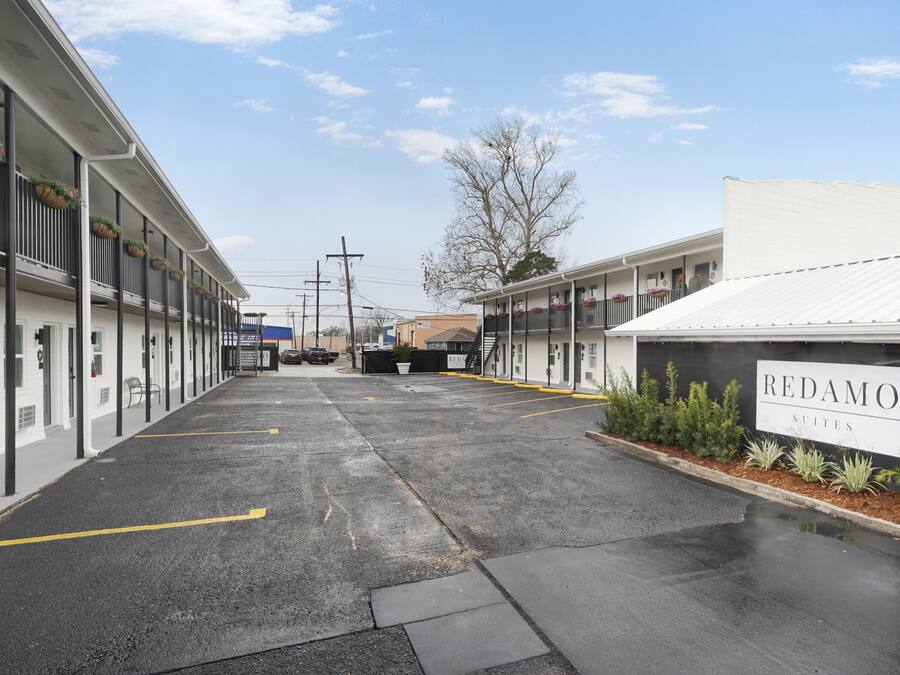 A Redamo Suites building with a parking lot in front.