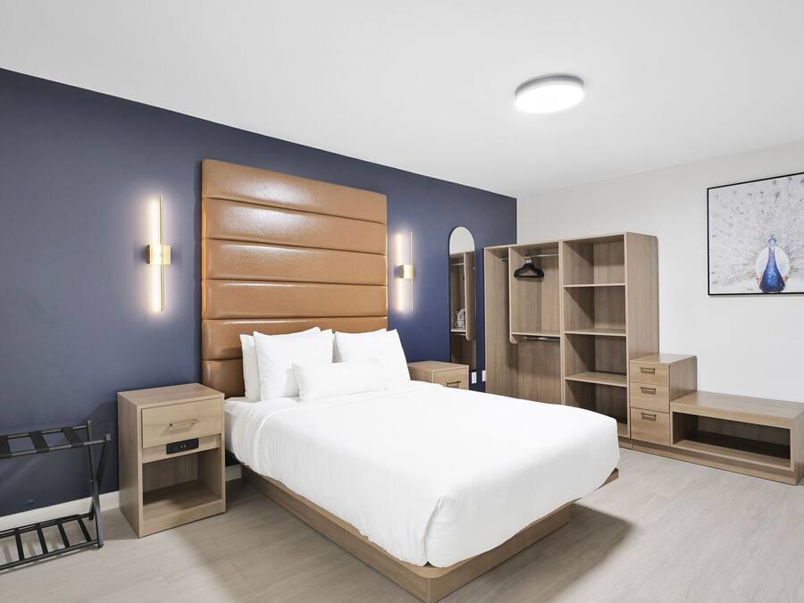 Camera da letto moderna con un letto grande, una testiera in legno, comodini, un armadio e un appendiabiti.