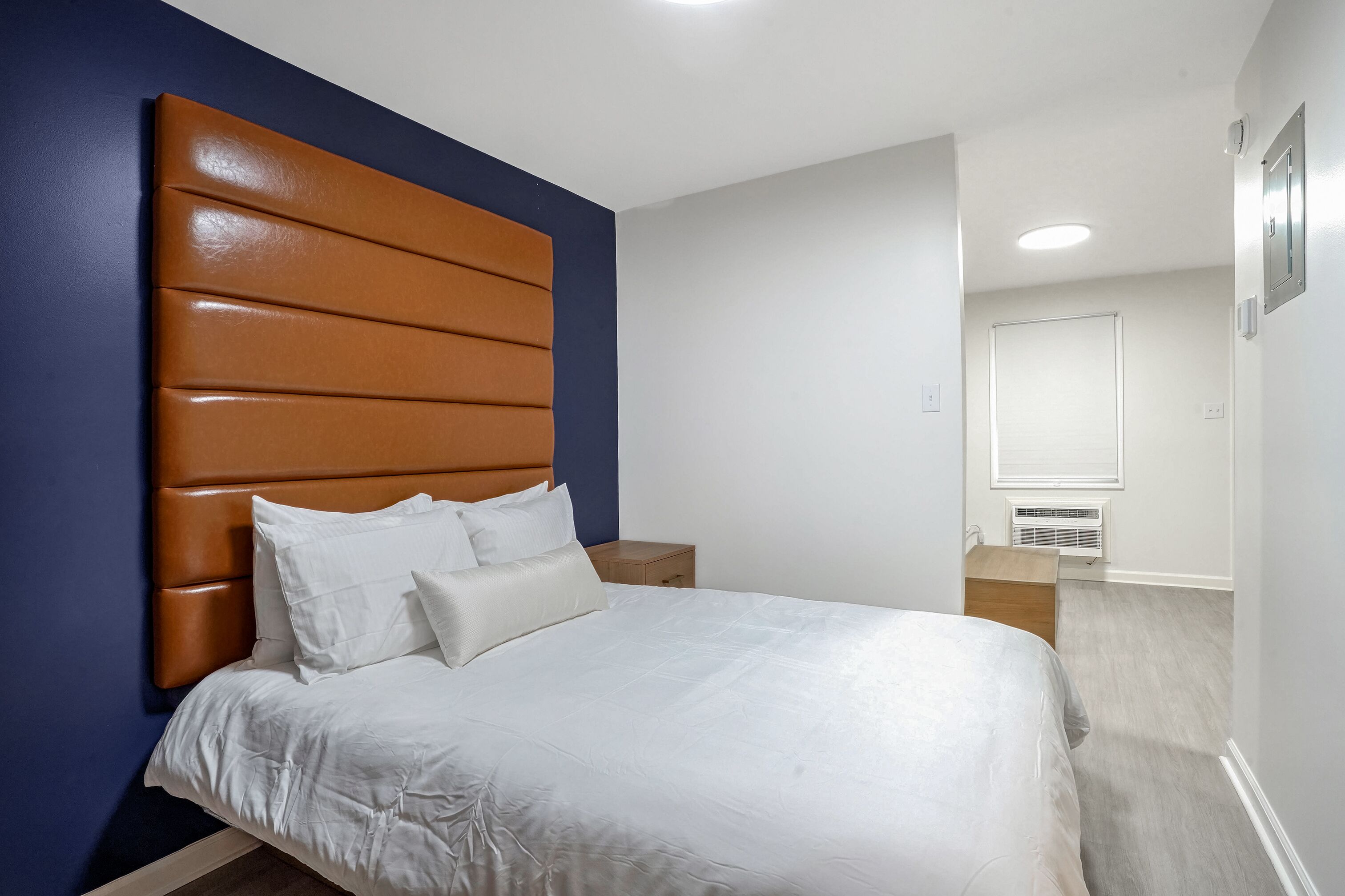 A bedroom with a large bed, a wooden nightstand, and a mirror.