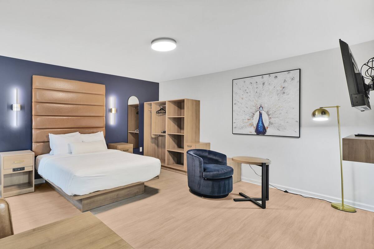 Une chambre à coucher moderne comprenant un lit, des tables de chevet, une armoire, une chaise et un bureau.