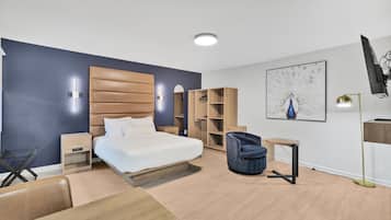 Un dormitorio moderno con cama, mesitas de noche, armario, silla y escritorio.