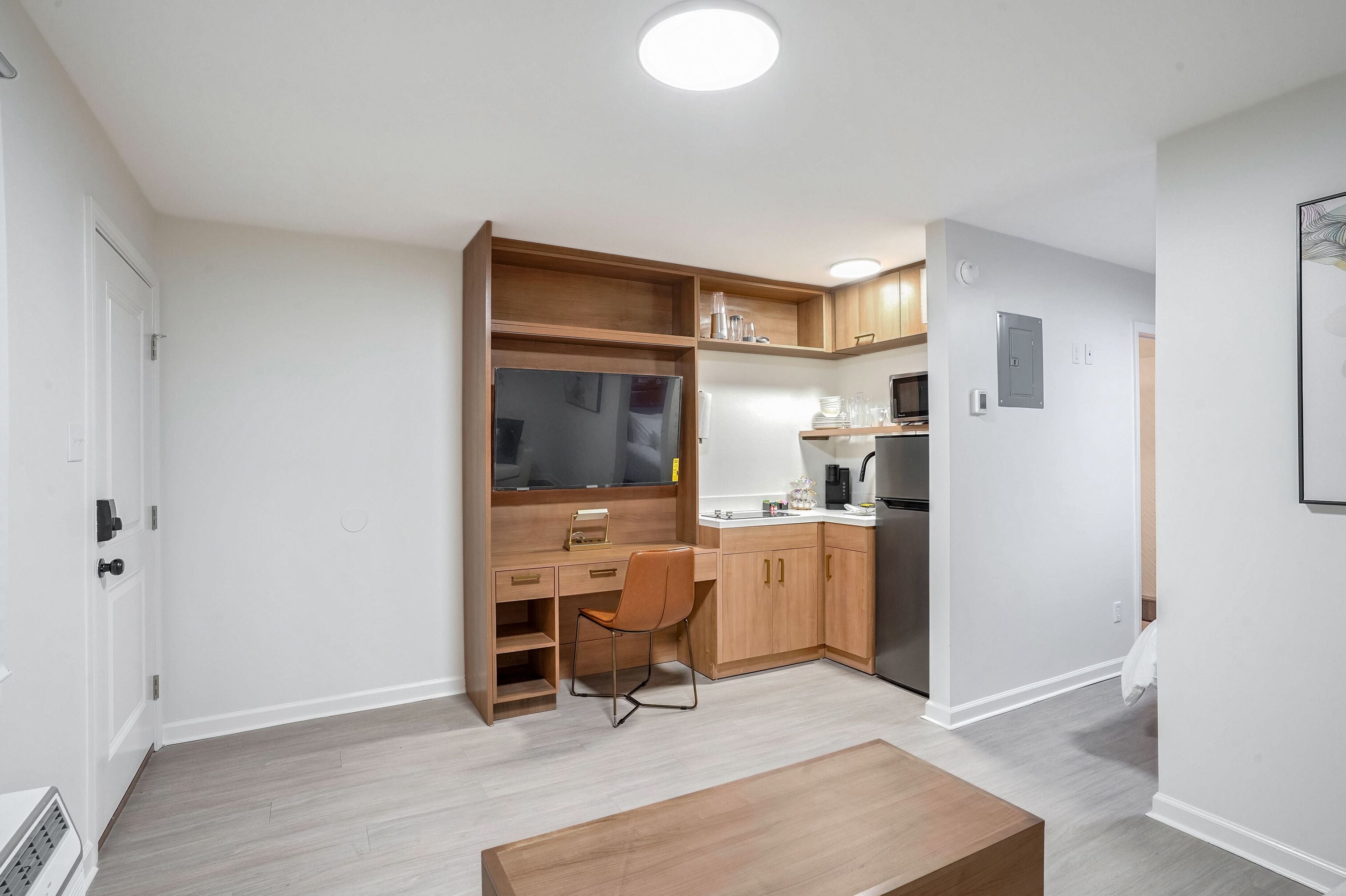 A compact kitchen with a built-in oven, microwave, and a small dining area with a wooden table and chair.