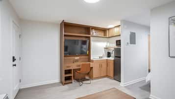 A compact kitchen with a built-in oven, microwave, and a small dining area with a wooden table and chair.