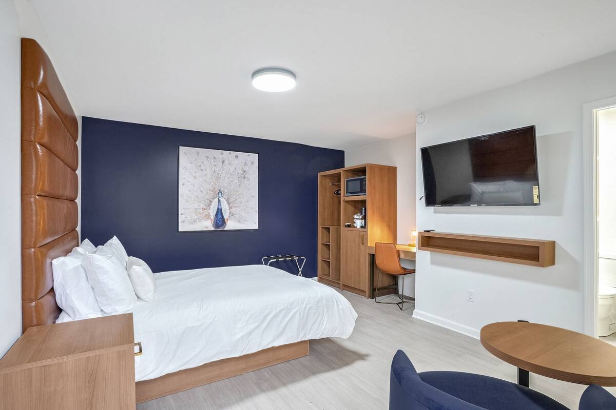 Une chambre d’hôtel moderne équipée d’un grand lit, d’un bureau, d’une télévision et d’une armoire.