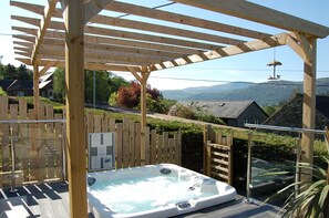 An outdoor hot tub under a wooden pergola with a wooden fence and a glass railing. - Paradwys in Dolgellau (Dolgellau)
