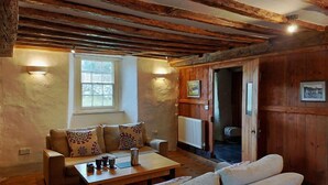 A cozy room with exposed wooden beams, a sofa set, a table with tea cups, and a window with a view. - Gallestra a Rustic, Rural Retreat Farm House Nr Dolgellau Snowdonia (Dolgellau)