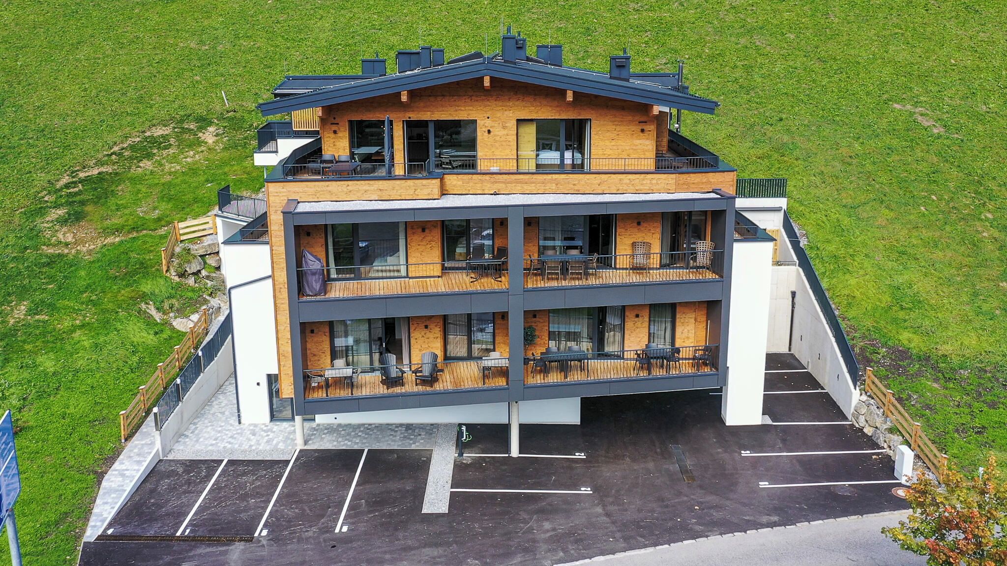 A modern multi-story hotel with a flat roof, large windows, and outdoor seating areas.