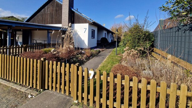 Une maison de plain-pied avec le numéro 7 sur le côté, une cheminée et une antenne parabolique.