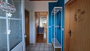 Un couloir avec un mur bleu, une porte en bois et une étagère blanche.