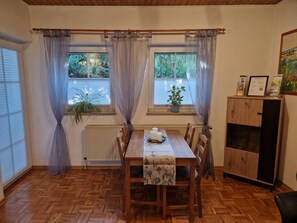 Een eetruimte met een houten tafel, stoelen en een raam met gordijnen.