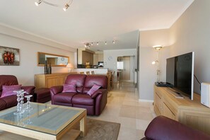 A modern living room with a glass coffee table, leather sofa, and a flat-screen TV. - Seafront Apartment in Blankenberge (Blankenberge)