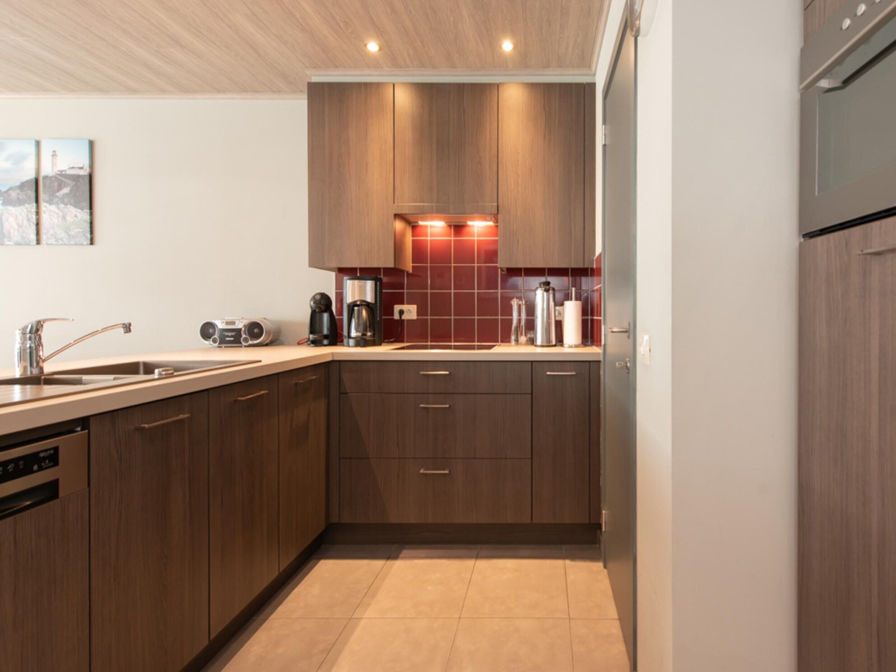 A modern kitchen with wooden cabinets, a built-in dishwasher, and a coffee maker.