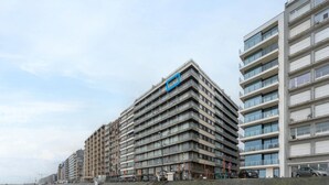 A row of multi-story buildings with balconies, a sandy ground, and a clear sky. - Studio in Blankenberge Near Beach & Pier (Blankenberge)
