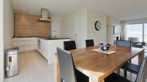 Eine moderne Küche mit einer Holzinsel, weißen Schränken und einem Essbereich mit Holztisch und -stühlen.