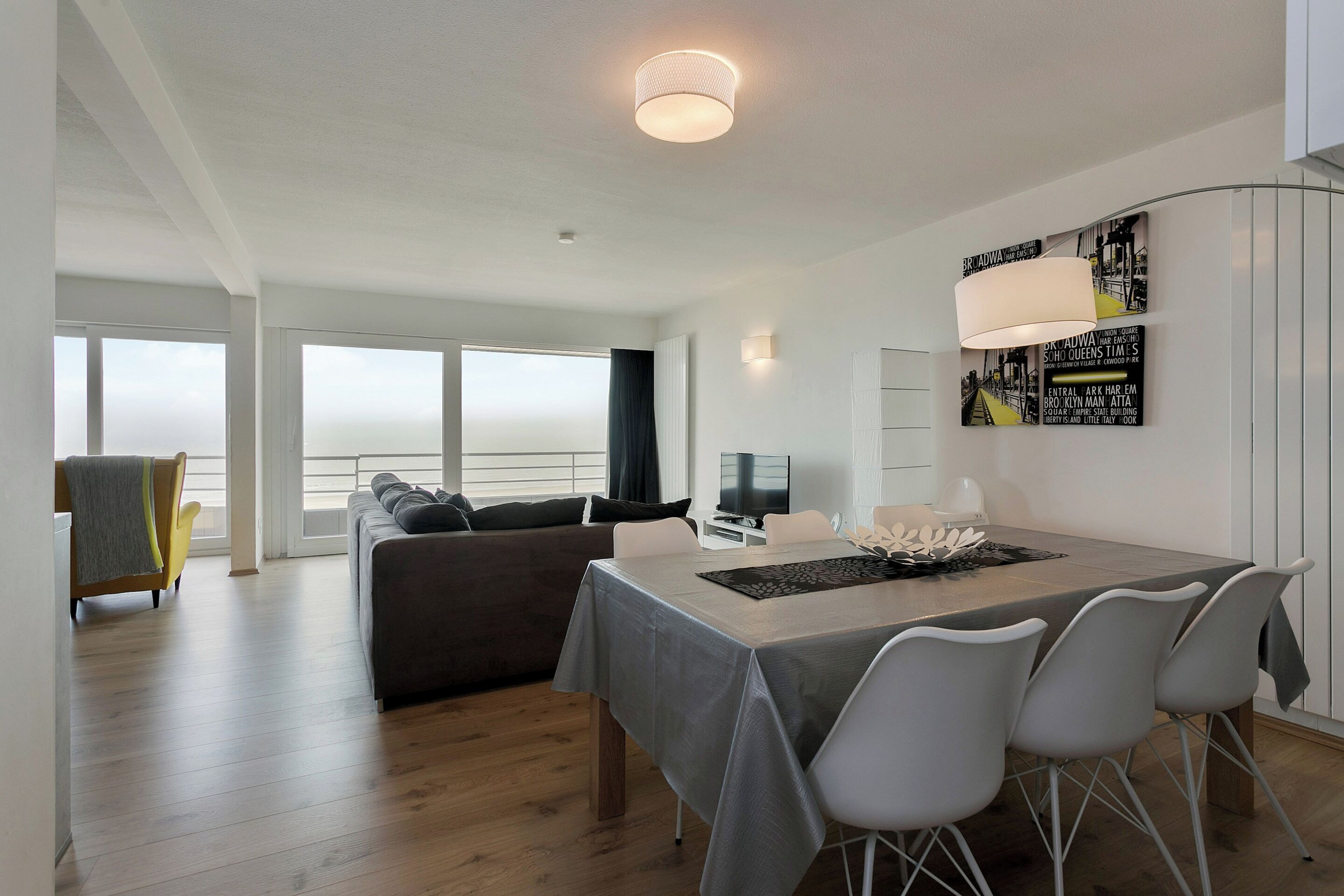 Una sala de estar moderna con comedor, ventanas amplias y un televisor de pantalla plana.