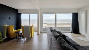 Ett modernt vardagsrum med ett stort fönster med utsikt över en strand.