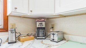 A kitchen with a coffee maker, toaster, and wooden box on a marble countertop.