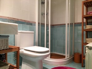 A bathroom with a toilet, a shower enclosure, and a shelf with towels. - Charming Apartment With Views In Las Margas Golf N001 (Sabinanigo)