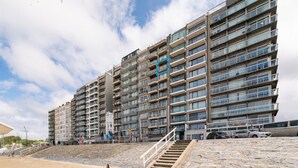 Un immeuble à plusieurs étages doté d’une architecture moderne, avec des balcons et de grandes fenêtres.