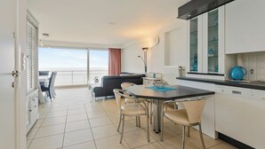 A modern kitchen with a dining area, a view of the sea, and a balcony with a sofa. - Luxbeach Apartment in Blankenberge (Blankenberge)