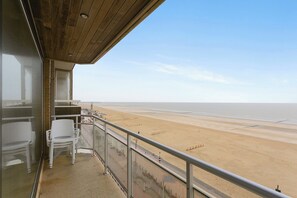 Un balcón con vista a una playa de arena y al océano.