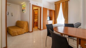 A hotel room with a bed, a dining table, chairs, a TV, and a bathroom visible through an open door. - Il Passetto (Rome)