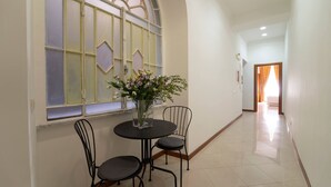A hallway with a dining area featuring a table and chairs, a vase with flowers, and a window with decorative glass panes. - Il Passetto (Rome)