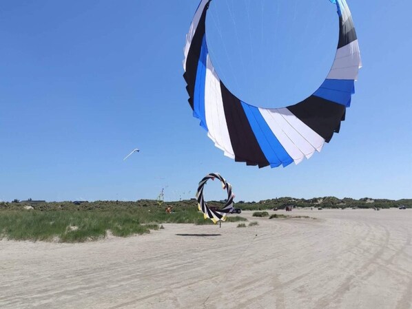 A sandy beach with a large, striped kite in the foreground and a clear blue sky. - 2 Person Holiday Home in Fano (Fano)