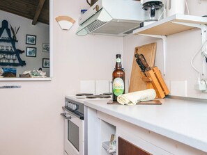 A kitchen with a stove, oven, and a bottle of beer on the counter. - 2 Person Holiday Home in Fano (Fano)