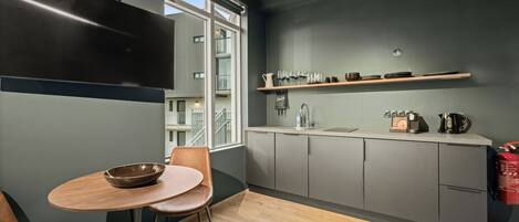 Una cocina moderna con armarios grises, una mesa de comedor de madera y una ventana con vistas a un balcón.