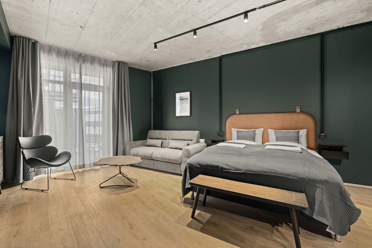 A modern bedroom with a bed, bench, and seating area.