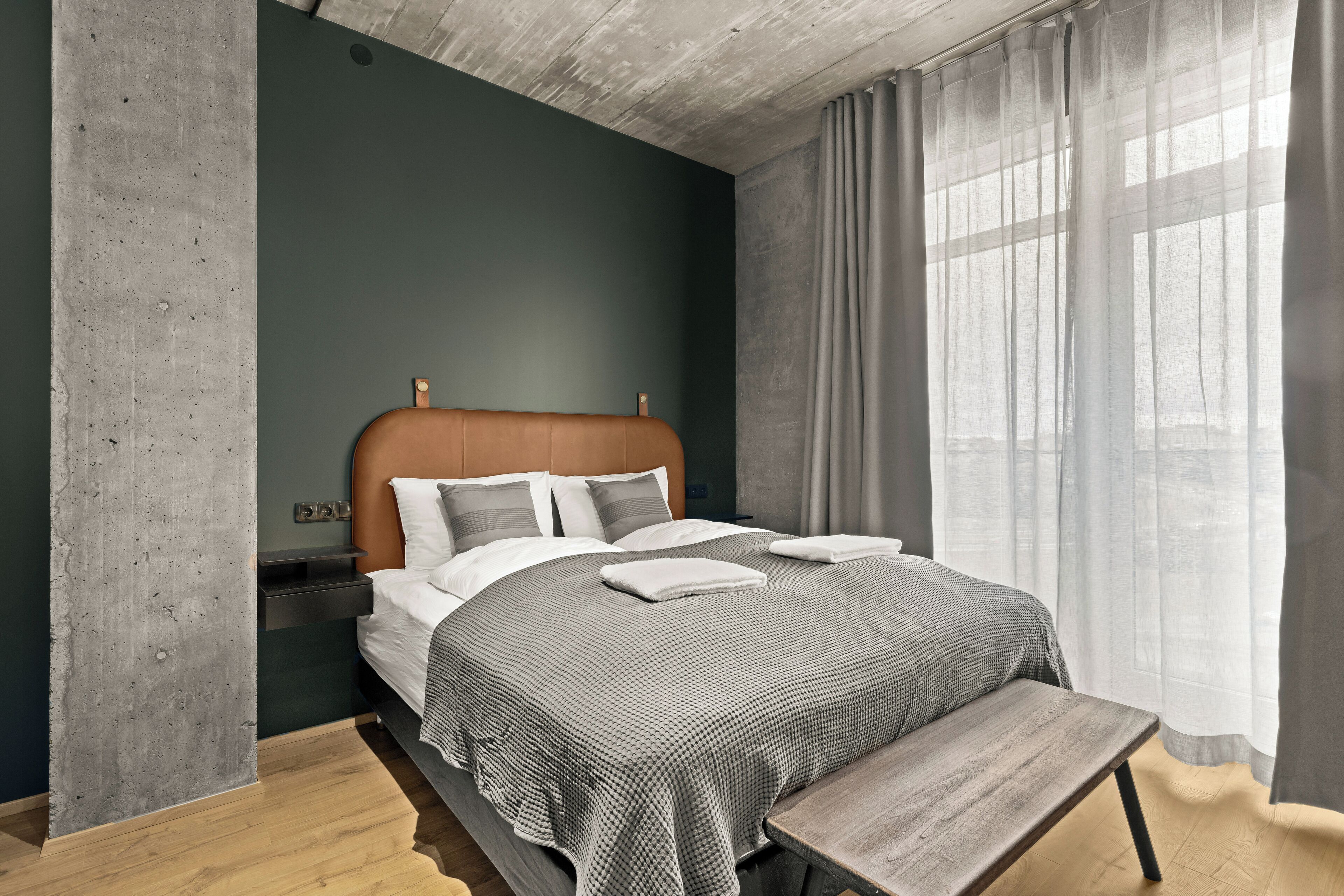 Ein modernes Schlafzimmer mit Bett, Nachttischen und einer Bank.