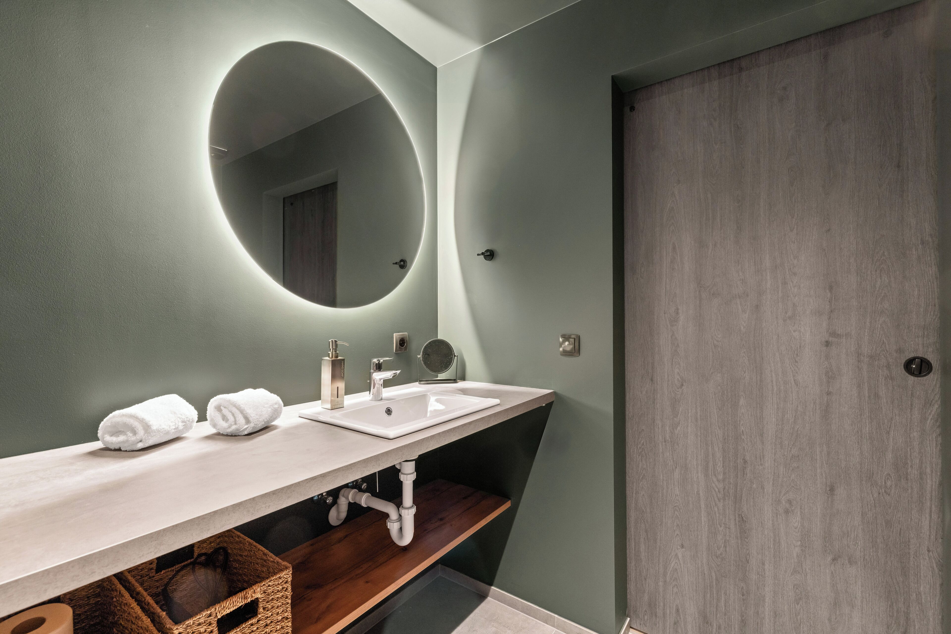 A modern bathroom with a large mirror, two sinks, and a wooden vanity.
