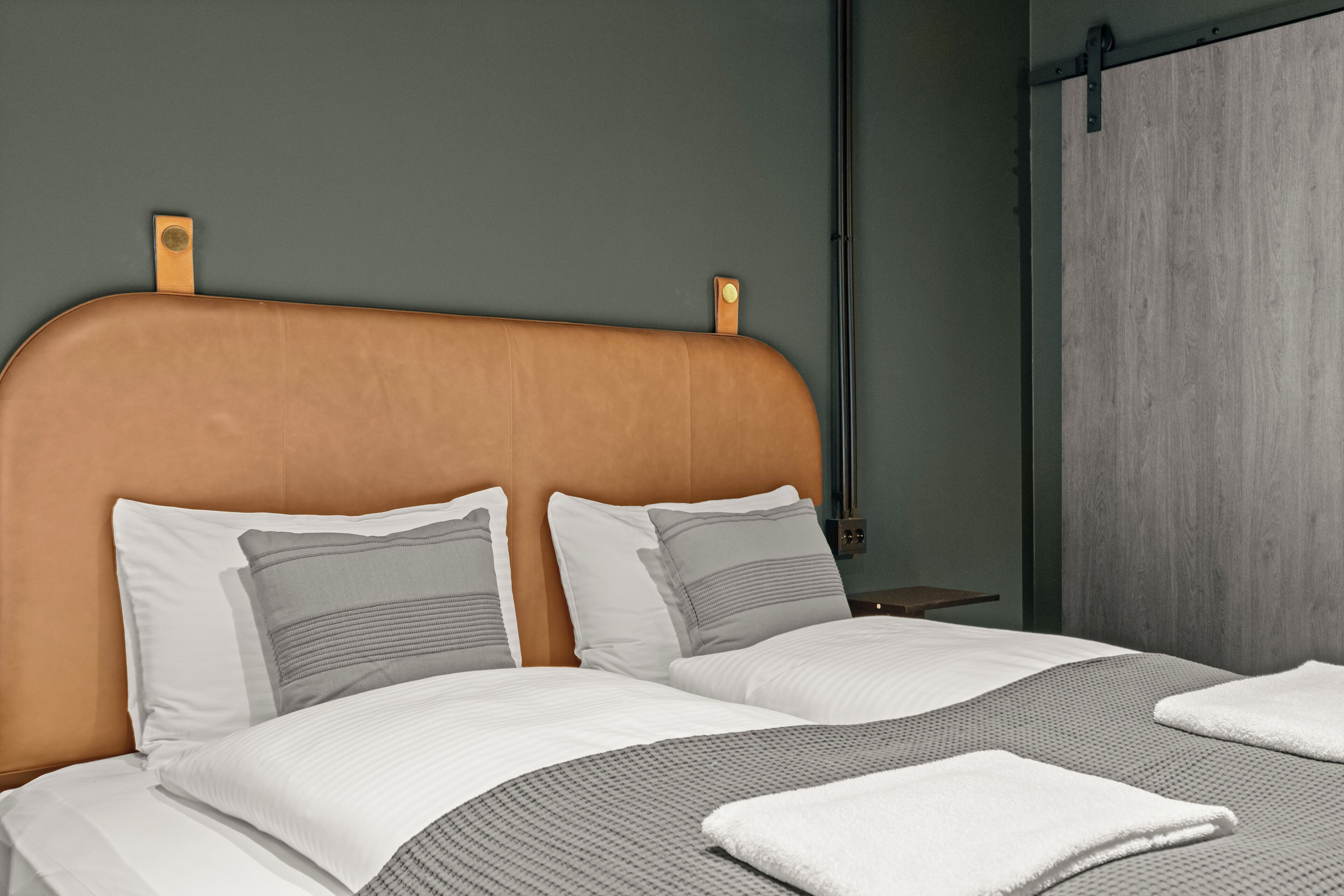 Una cama bien hecha con tablero de madera, dos almohadas y una colcha.