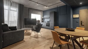 A modern living room with a sofa, chairs, a dining table, and a kitchen area with cabinets and appliances. - Aurora Nooks (Kópavogur)