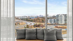 A view from a window with a cityscape, including roads and buildings, and a seating area with cushions. - Aurora Nooks (Kópavogur)